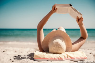 Frau lesend am Strand